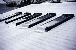 Snowfall slidiing from skylight glass.